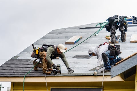Crew installing shingles on rainy day