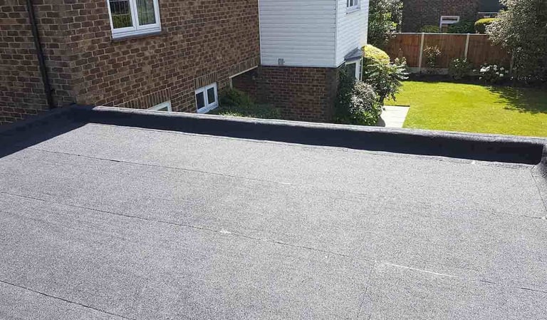 New patio with gray concrete pavers against brick house with manicured yard in background