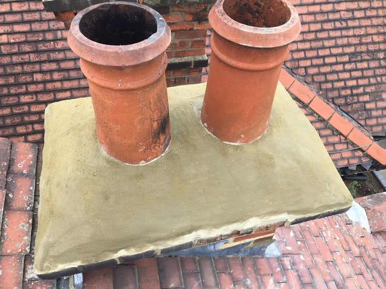 Two terracotta chimney flues mounted on a lead-lined concrete base on a brick roof