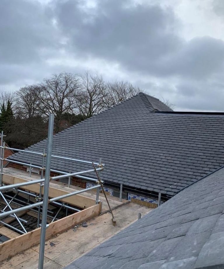 New roof installation with metal scaffolding and dark gray shingles on residential home under construction