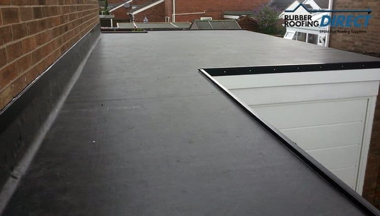 Flat commercial roof with gray membrane coating, white ventilation unit, and brick wall perimeter