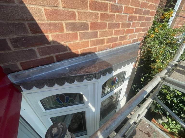 White door frame with ornate black trim against red brick wall in bright sunlight